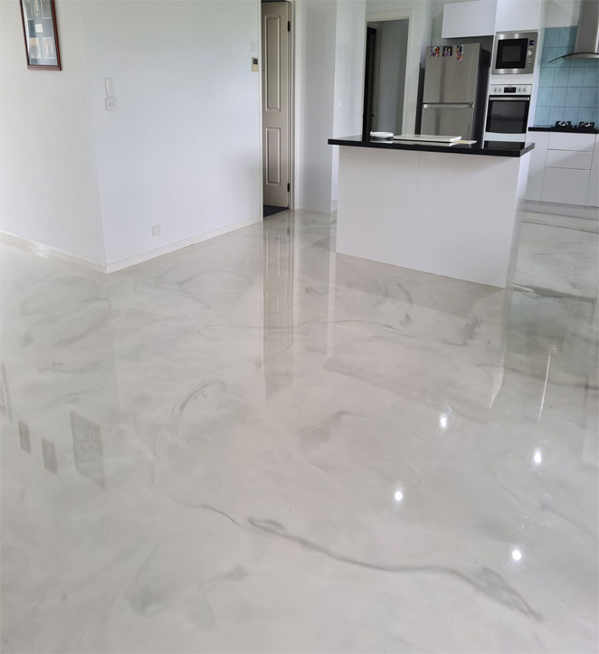 Vacant kitchen area with white walls, countertops, and shiny epoxy floor.