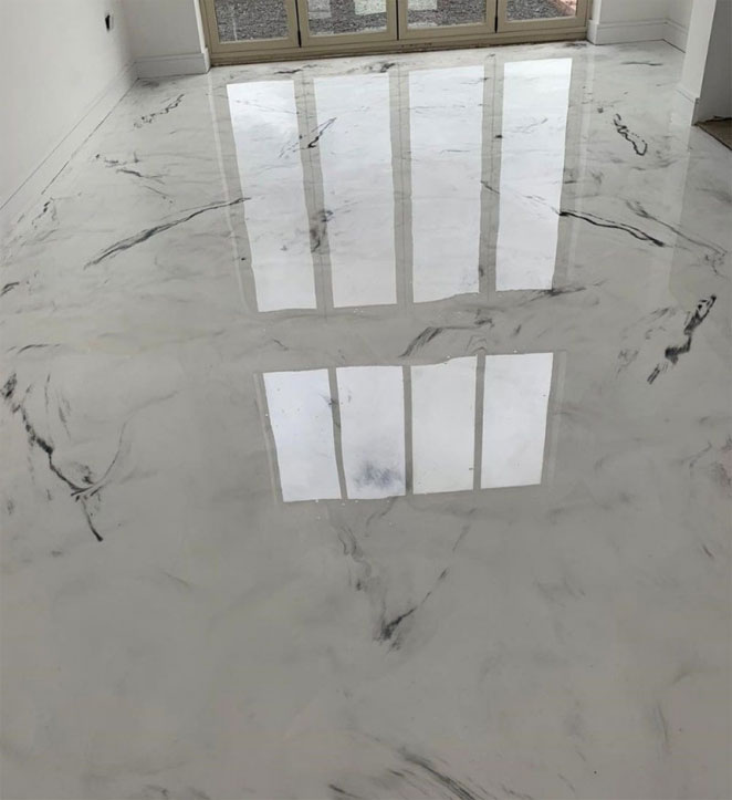 A shiny epoxy floor reflecting the silhouette of a window.